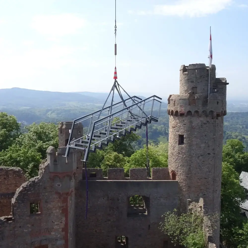 Ein Hubschrauber hebt ein Bauteil der Steganlage in die Burg