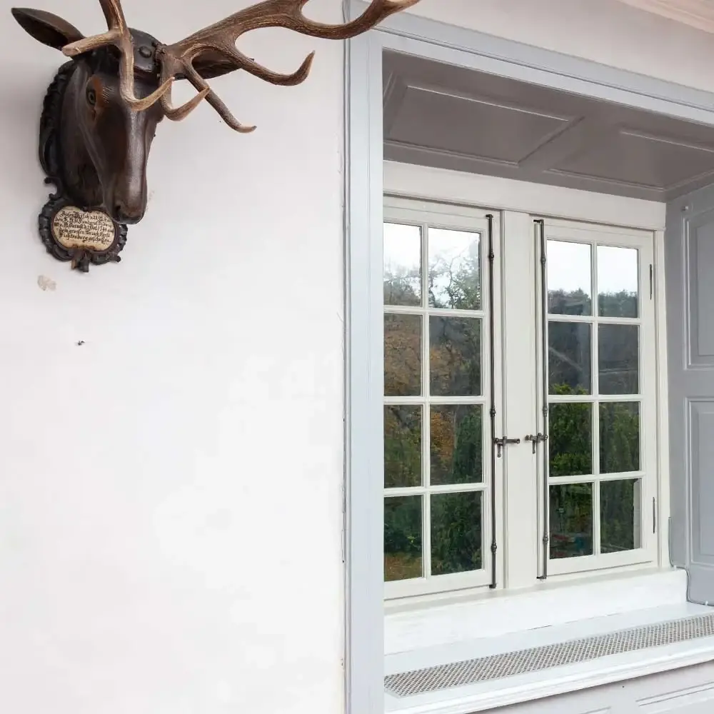 Geweih an der Wand neben einem Sprossenfenster