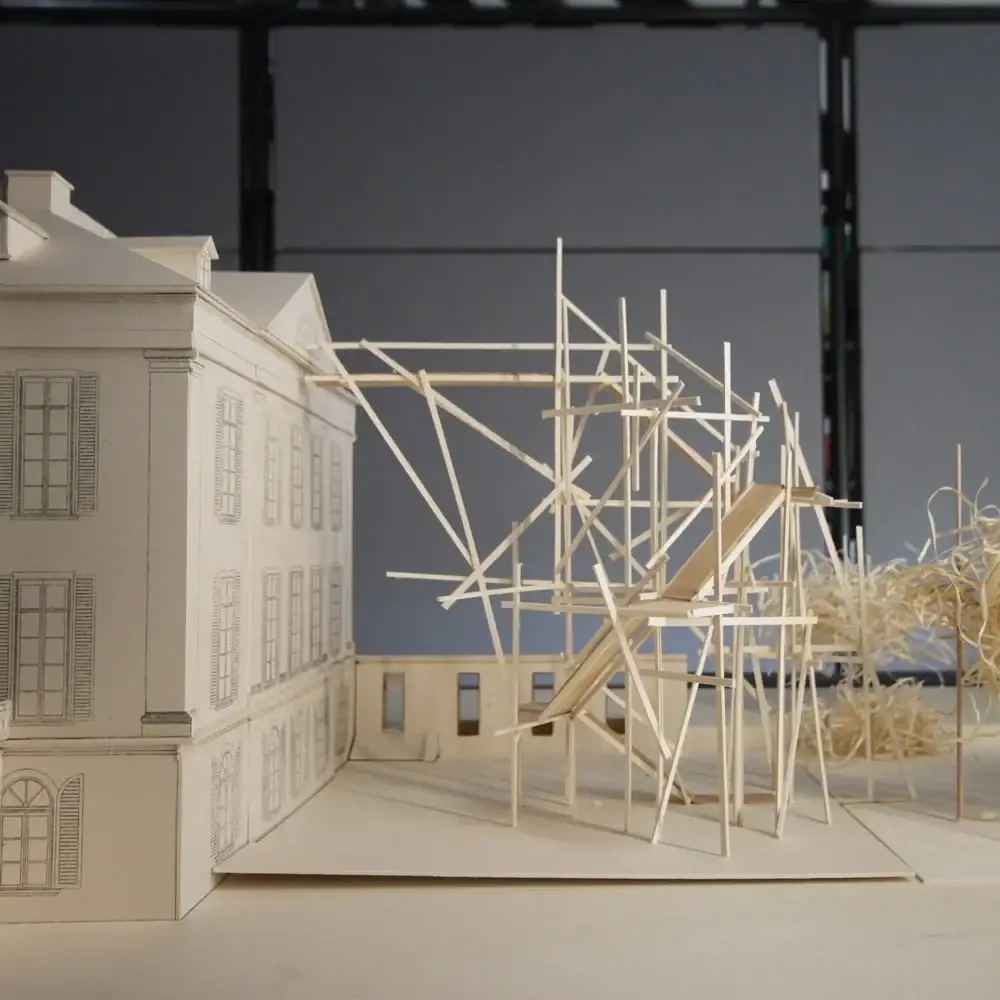 Modell eines Gerüsts aus Holzstäben vor der Schlossfassade