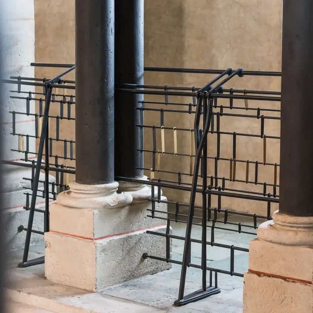 Nahaufnahme: Rundstahl und Messingverbinder vor einer romanischen Säule