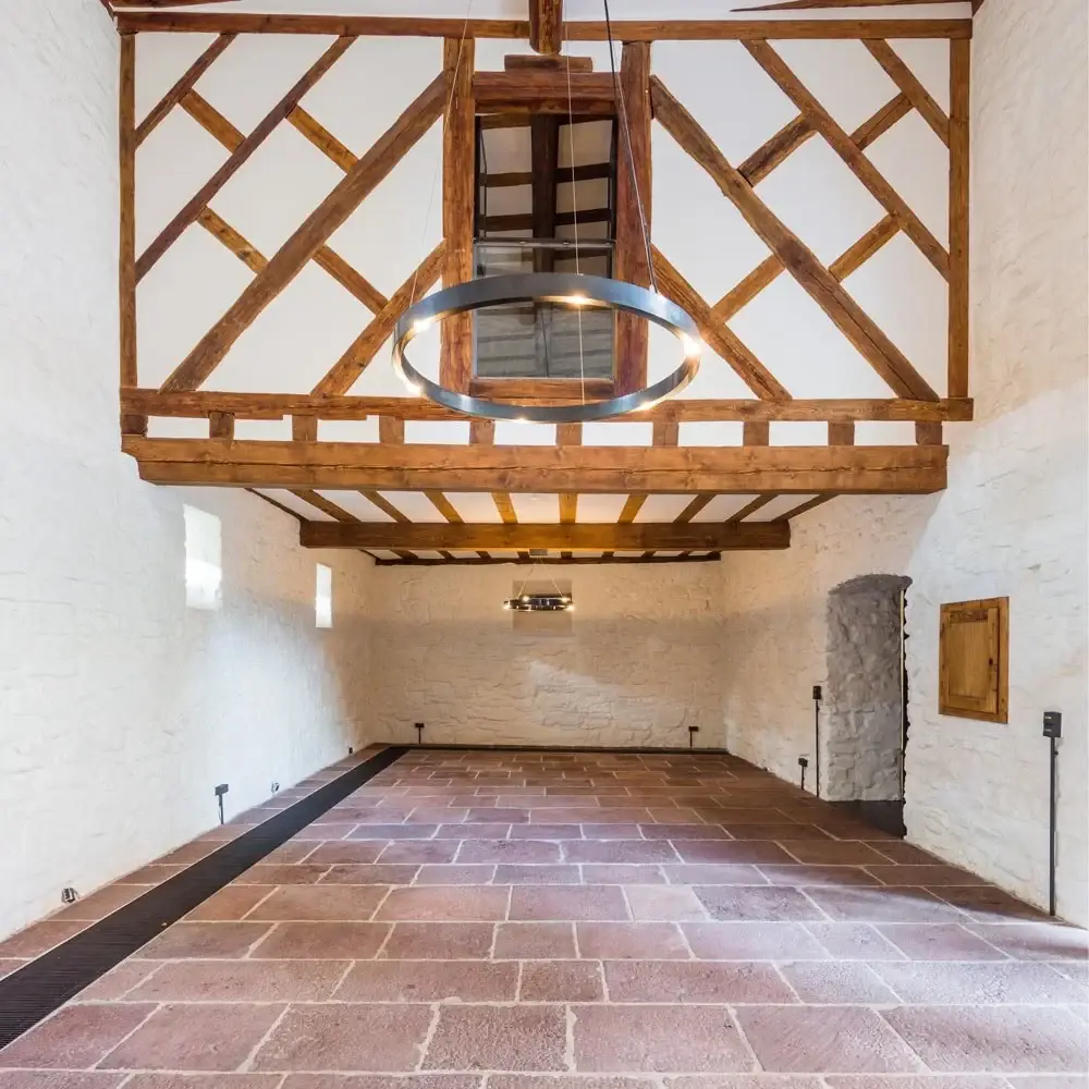 Saal der Mittelburg: Fachwerk unter der Decke, darunter eine schlichte Ringleuchte