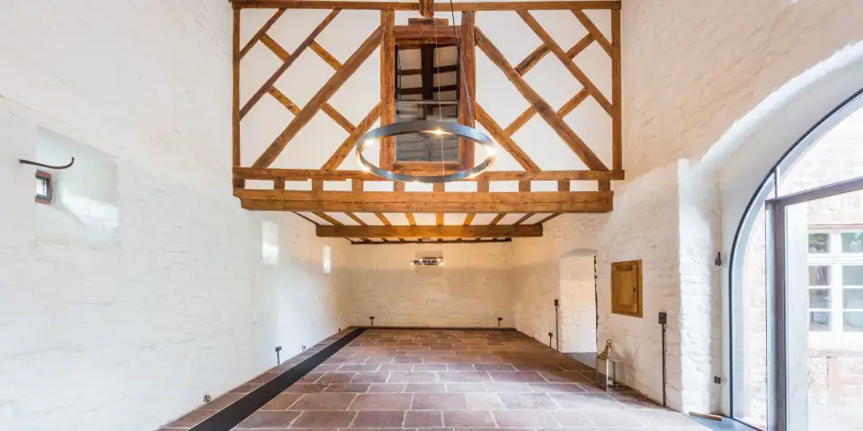 Festsaal der Mittelburg mit freigelegtem Fachwerk, Sandsteinboden und Ringleuchte