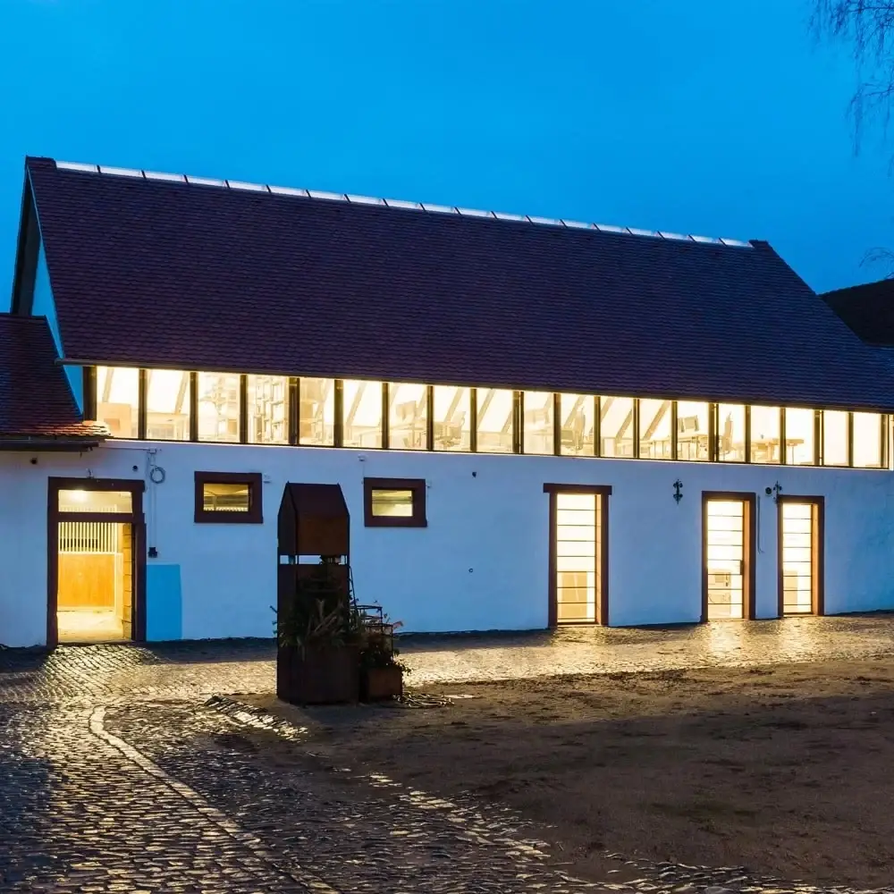 Büro Kaffenberger in Dilshofen am Abend, beleuchtetes Obergeschoss
