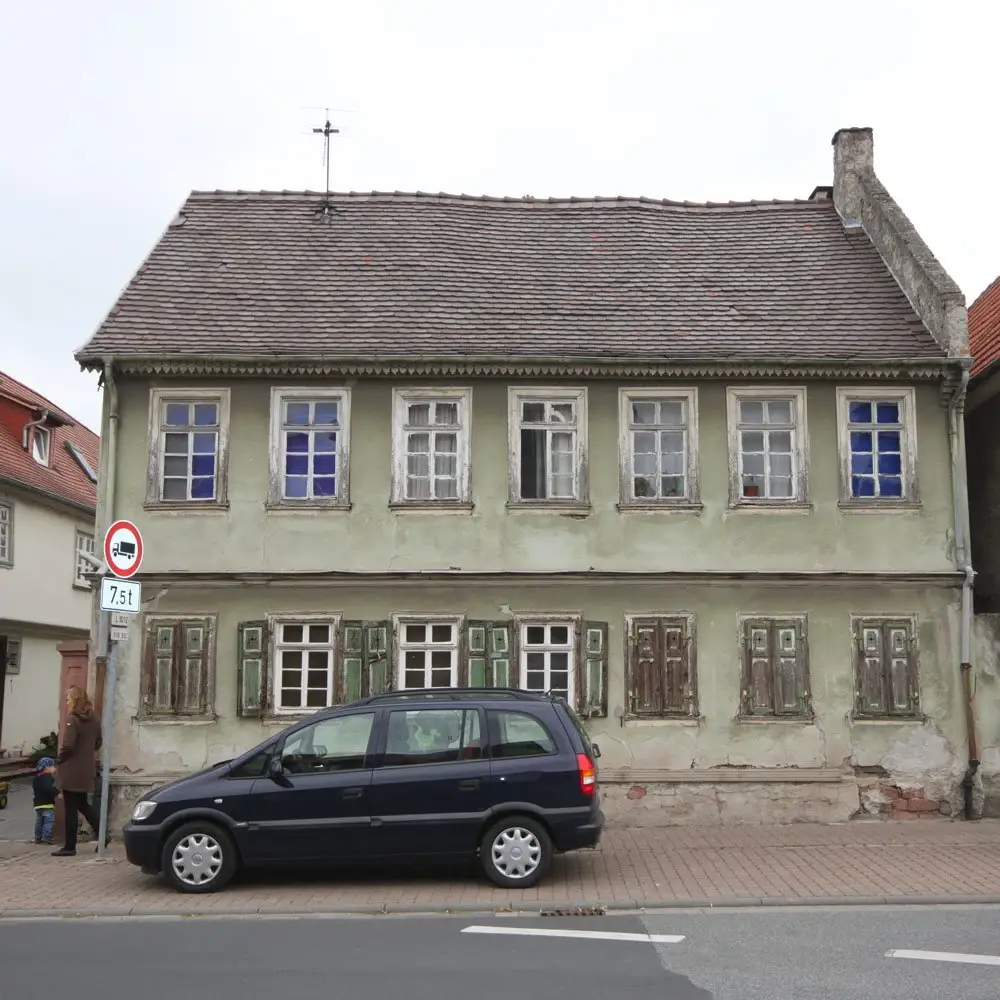 Wohnhaus in Trebur vor der Sanierung: verwitterte Fassade, graue Läden