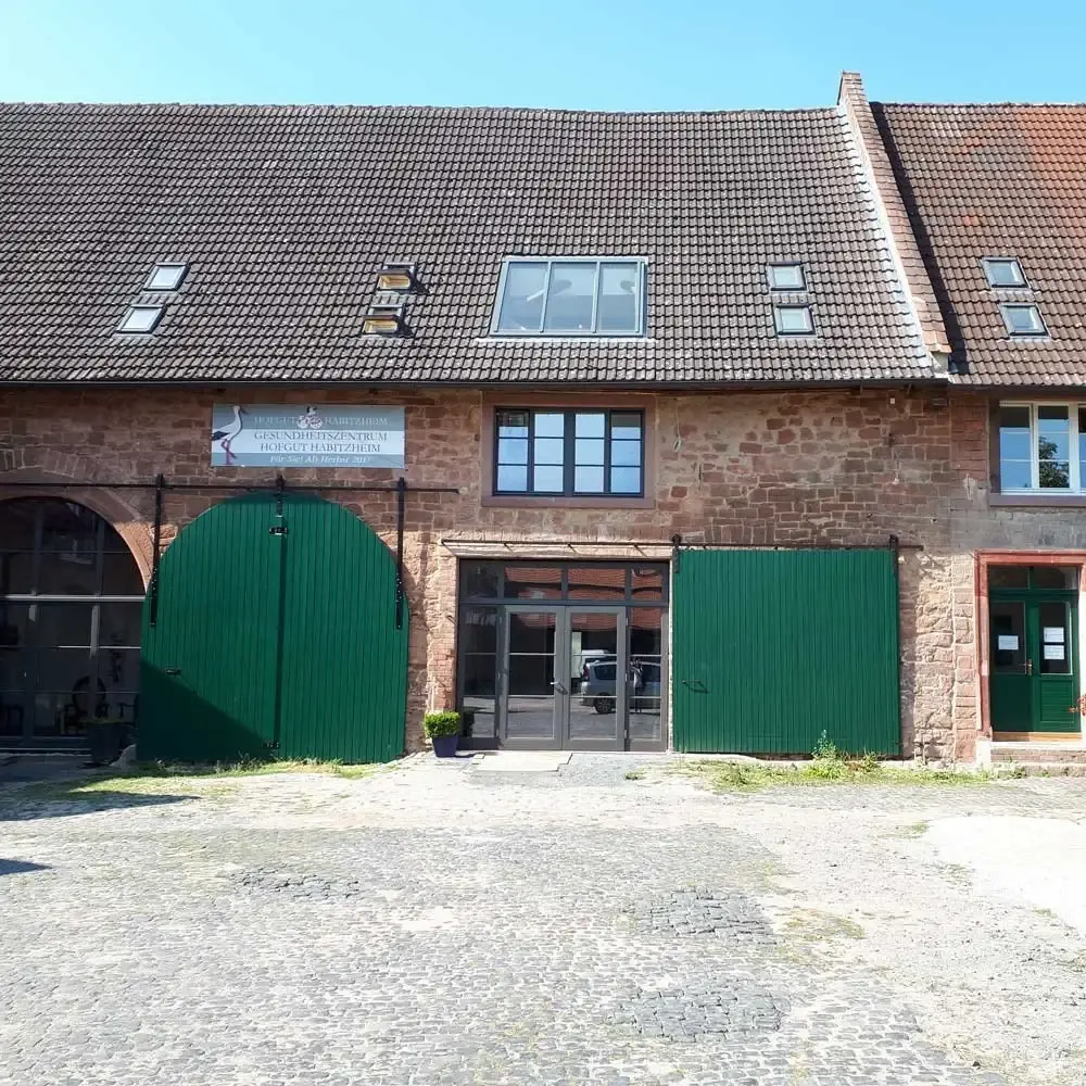 Wirtschaftsflügel des Hofguts Habitzheim mit grünen Toren