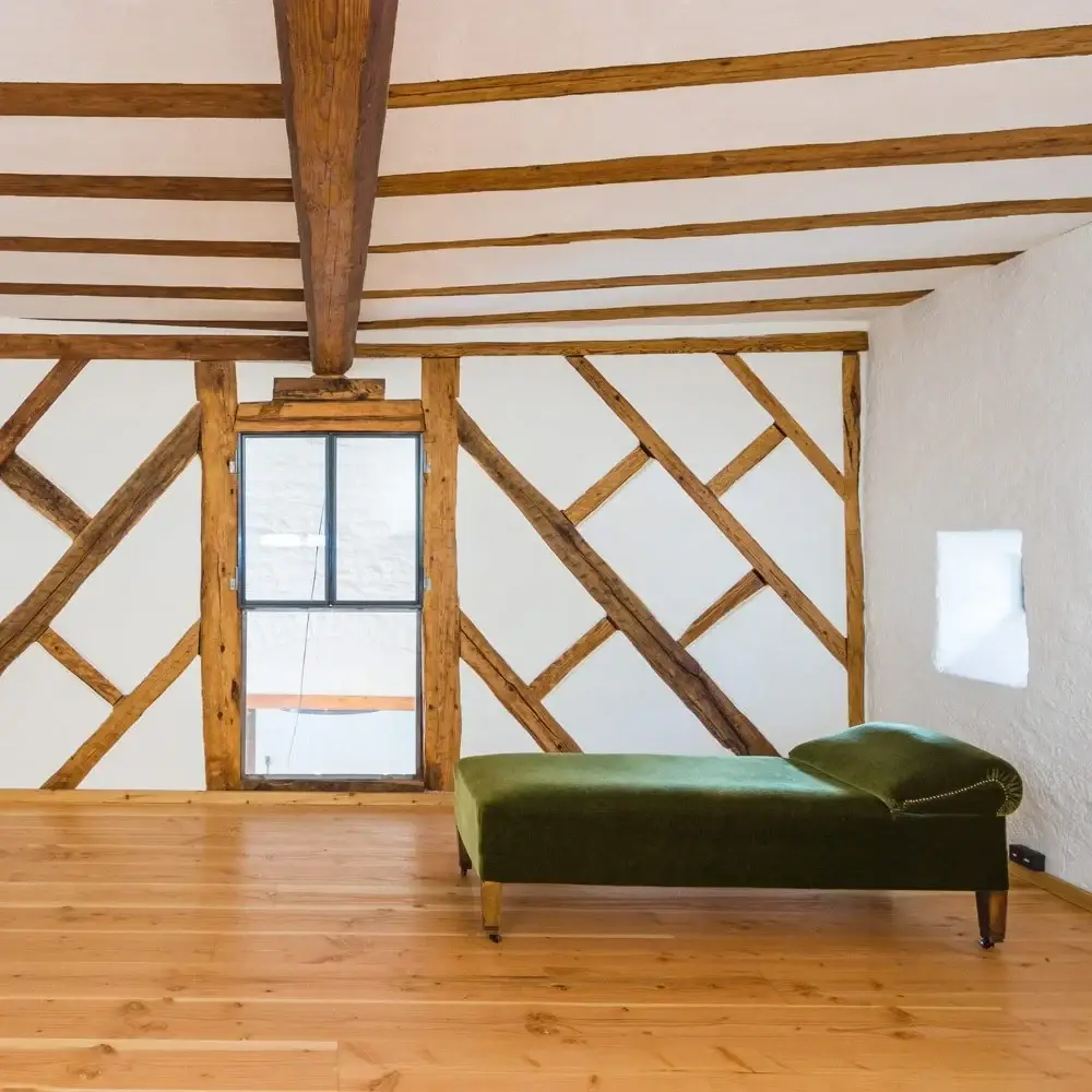 Gästezimmer mit Fachwerkwand, Holzdielen und grünem Sofa